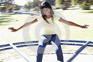 Teenager Girl Sitting On Playground Roundabout