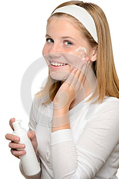 Teenager girl smiling applying moisturizer lotion