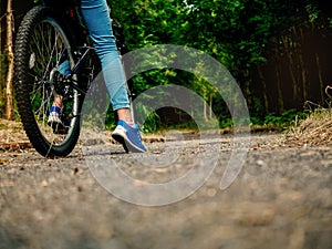 Teenager girl standing with her foot and bike on a path into dark scary forest. Concept risk evaluation, scary unknown, adventure