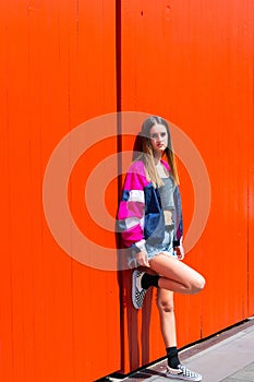 Teenager girl standing and leaning against bright orange doors