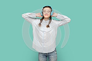 Teenager girl standing listening favorite music with headphones, closed eyes and smiling.