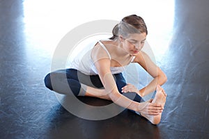Teenager, girl and stretching foot in class, floor and training in fitness studio, movement and exercise. Female person