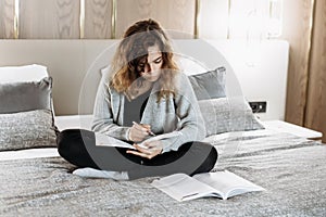 Teenager girl studying on the bed at home. Student doing homework