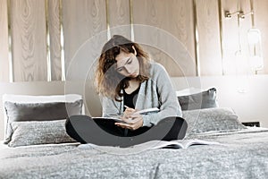 Teenager girl studying on the bed at home. Student doing homework