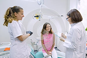 Teenager girl talking with doctors dentists sitting in the dental office. Medicine, dentistry and healthcare concept