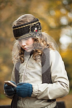 Teenager girl texting with cellphone in an autumn day