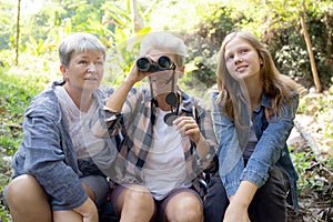 Teenager girl and two grandmother traveling travel to forest and adventure while using binoculars exploration.