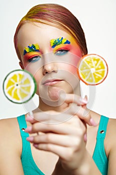 Teenager girl with unusual face art make-up . Child trying to choose between two lollipops