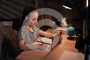 Teenager girl using tablet computer learning distantly online sitting at night at home. Web education and e-learning