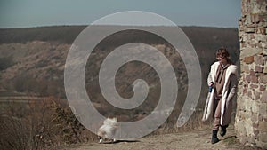 Teenager girl walking with her little dog Pomeranian spitz towards the hills