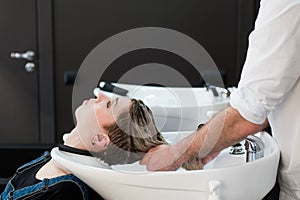 Teenager girl washing hair in hairdressing salon.