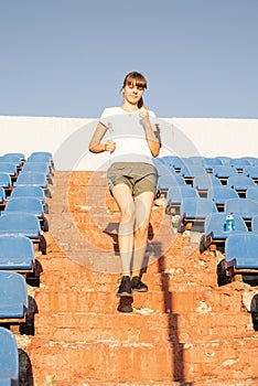 Teenager girl working out at the staduim running down the stairs