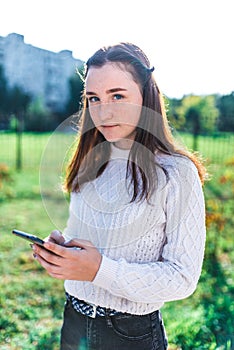 Teenager girl 12-15 years old portrait, in summer city, in hand smartphone, outdoor recreation after lessons in college