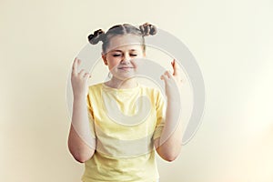 Teenager girl in a yellow T-shirt crossed her fingers