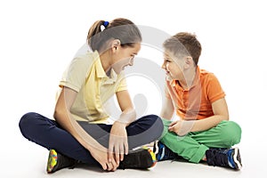 A teenager girl with a younger brother are sitting opposite each other. White background