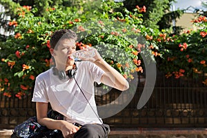 Teenager guy drinking water from bottle and removing thirst on hot summer day