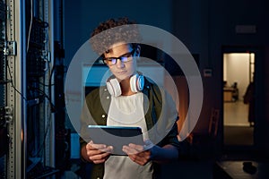 Teenager guy IT technician working on tablet in server room