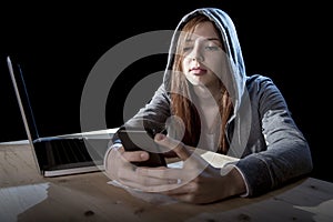 Teenager hacker girl in hood using mobile phone in internet cyber crime expert or cybercrime