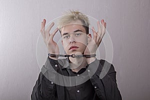 A teenager in handcuffs on a gray background. juvenile delinquents in quarantine, criminal liability. Members of youth criminal gr