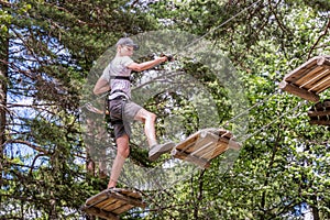 Teenager having fun on high ropes course, adventure, park, climbing trees in a forest