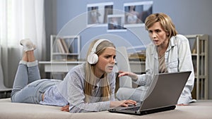 Teenager in headphones ignoring mother, surfing net, difficult puberty age
