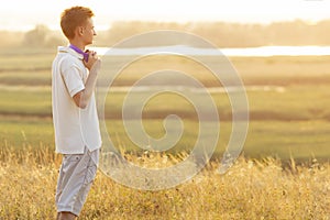 Teenager in headphones listening to music on nature, face profile of young man looking in the distance and enjoying of a beautiful