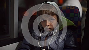 A teenager in headphones rides in a passenger seat on a public transport bus.