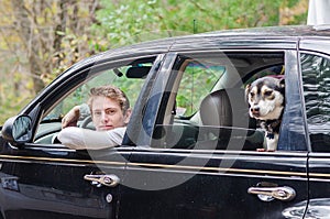 Teenager in in his car with dog in backseat