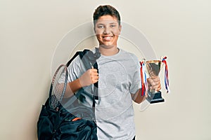 Teenager hispanic boy holding sport bag holding trophy smiling with a happy and cool smile on face