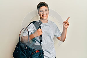 Teenager hispanic boy holding sport bag smiling happy pointing with hand and finger to the side