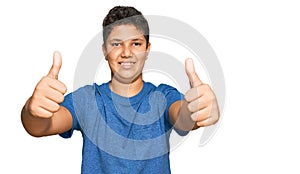 Teenager hispanic boy wearing casual clothes approving doing positive gesture with hand, thumbs up smiling and happy for success