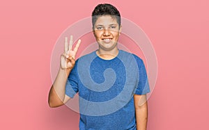 Teenager hispanic boy wearing casual clothes showing and pointing up with fingers number three while smiling confident and happy