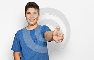 Teenager hispanic boy wearing casual clothes smiling friendly offering handshake as greeting and welcoming