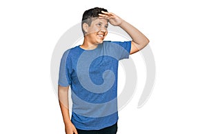 Teenager hispanic boy wearing casual clothes very happy and smiling looking far away with hand over head