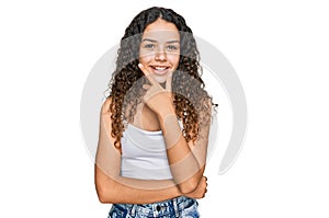 Teenager hispanic girl wearing casual clothes looking confident at the camera smiling with crossed arms and hand raised on chin