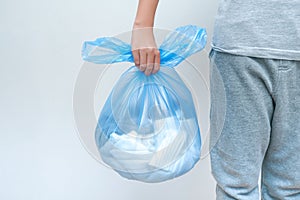 A teenager holding a big plastuc bag af clothes for recycling, copy space