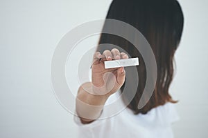 Teenager holding pregnancy test cassette with positive result