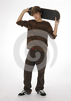 Teenager holding skateboard behind head