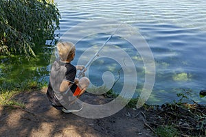 A teenager holds a fishing rod and watches a fish nibble. Sport fishing on the river in summer