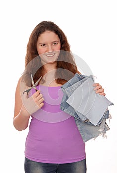 Teenager holds scissors and pieces of jeans.