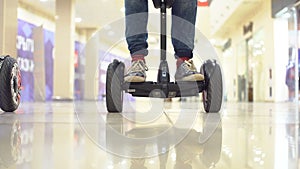 Teenager on hyroscooter in a modern shopping center. Close up of man`s legs on two wheels electric gyro scooter. photo
