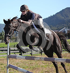 Teenager jumping black horse