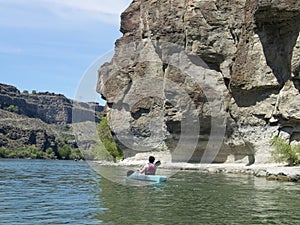 Teenager kayaks by rocky shore