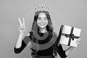Teenager kid with present box. Teen girl princess in crown giving birthday gift. Present, greeting and gifting concept photo