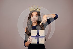 Teenager kid princess in crown with present box. Teen girl giving birthday gift. Present, greeting and gifting concept