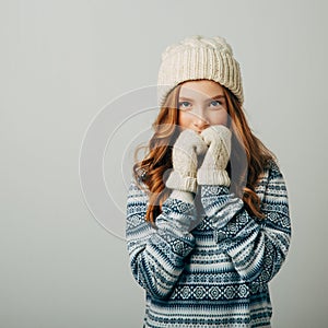 Teenager in a knitted hat, sweater and gloves. She is very warm and comfortable in this dress. The girl is very glad not