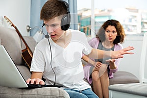 Teenager with laptop making stop gesture to mother