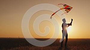 A teenager launches a kite at sunset.