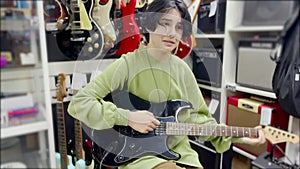 a teenager learns to play the electric guitar in a music store. rock music training band concept. Teenage guitarist