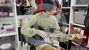 a teenager learns to play the electric guitar in a music store. rock music training band concept. Teenage guitarist